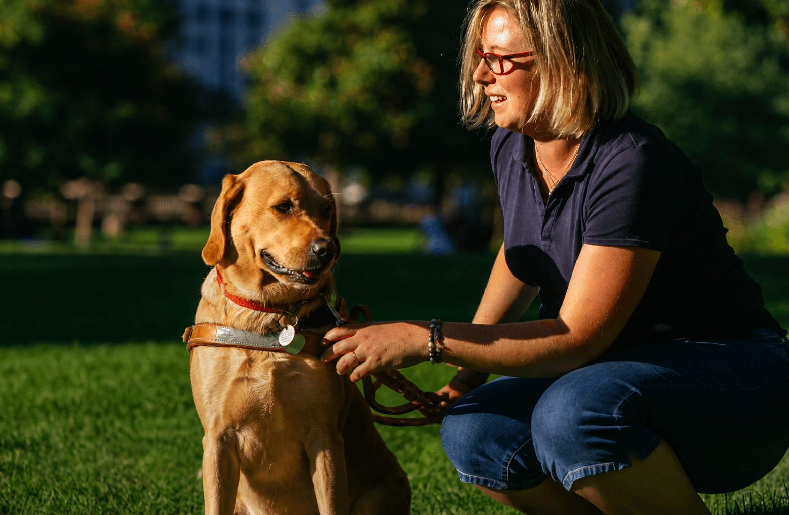 Une femme accompagnée de son chien guide dans un parc